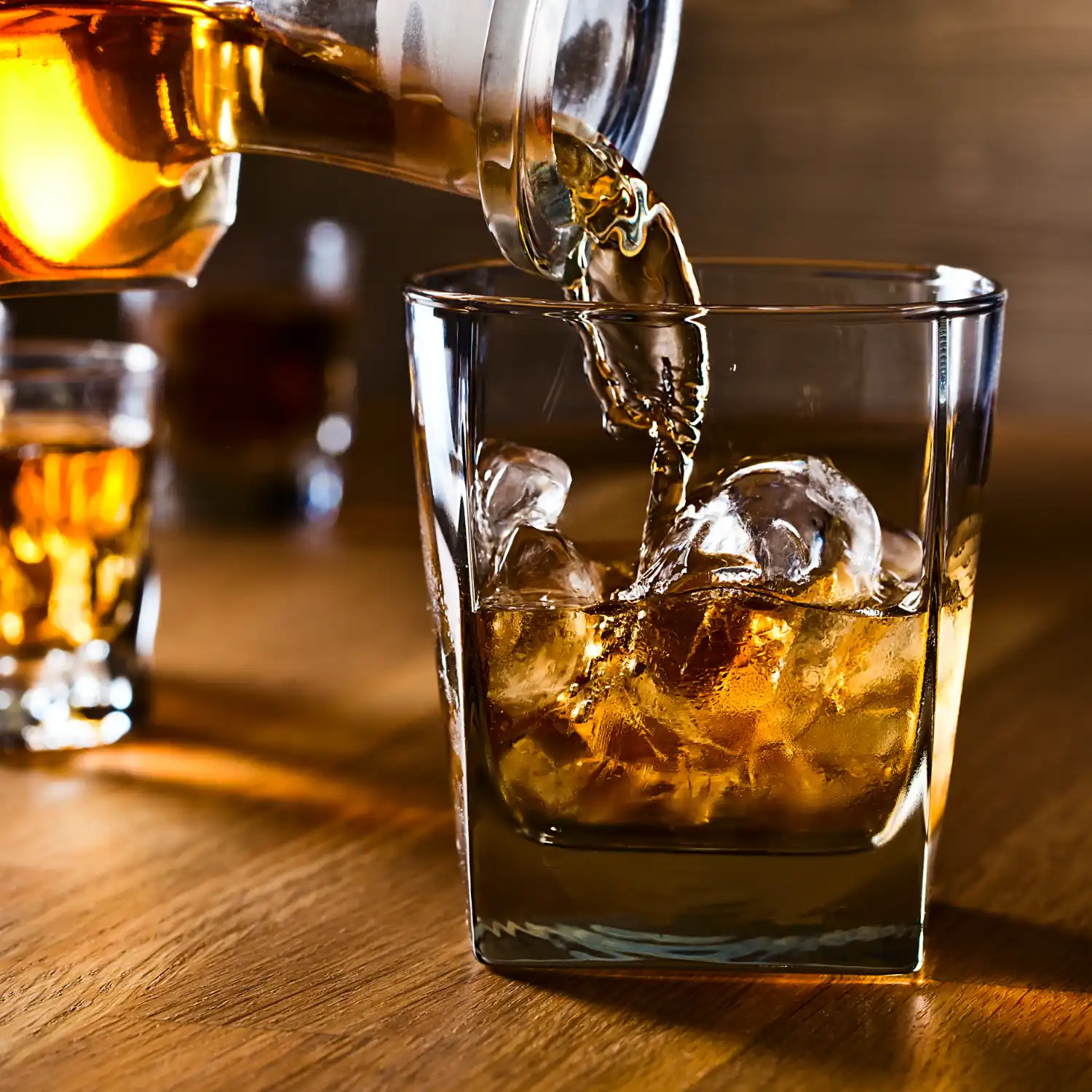 Bourbon being poured over ice in a glass.