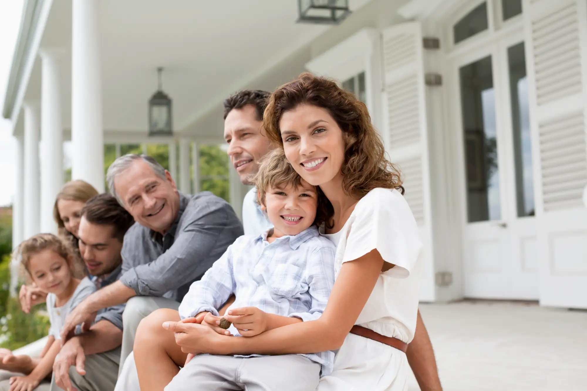 A multi-generational family of seven sitting on a large front porch.