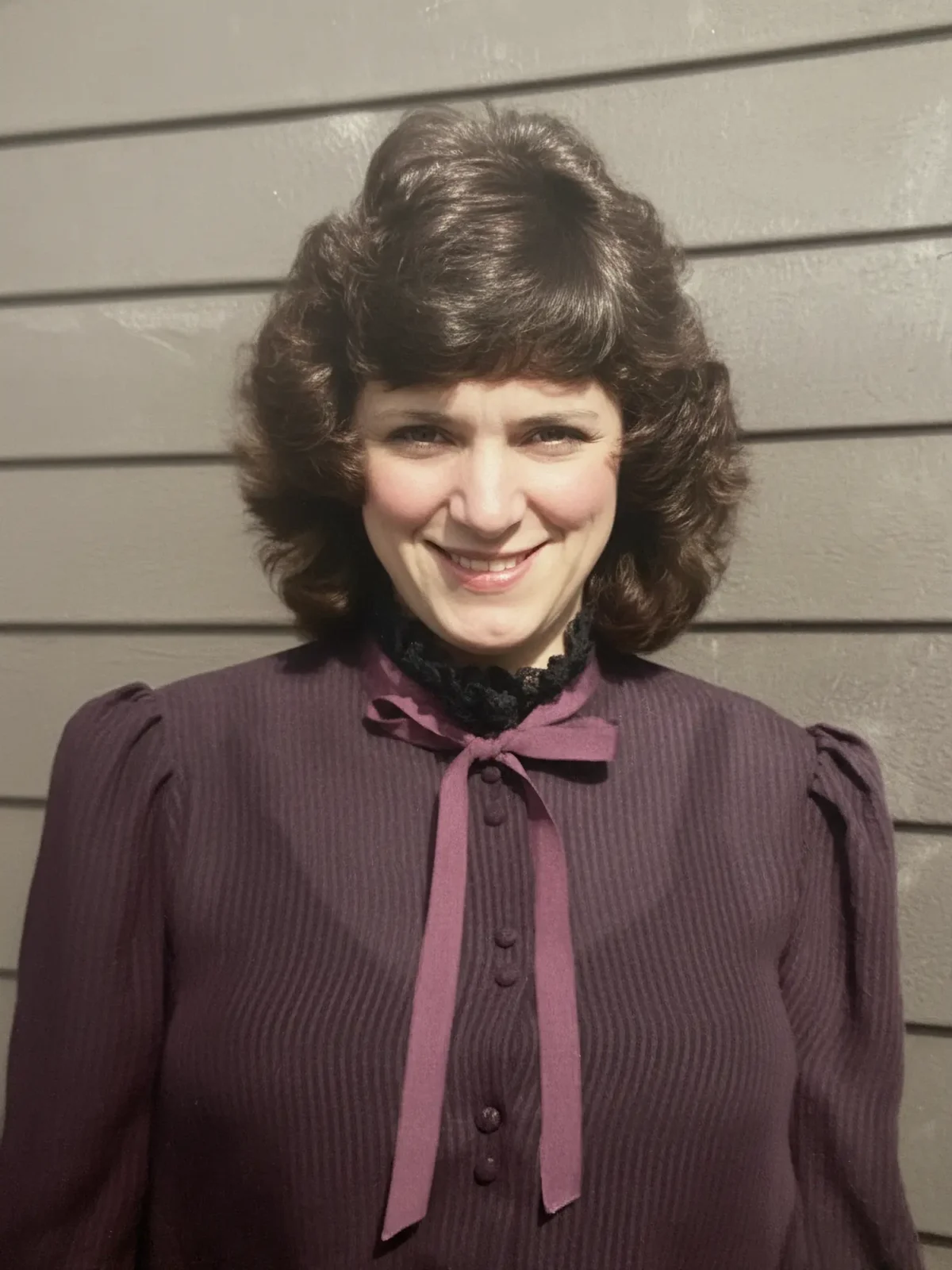 Penny VanNortwick as an adult; a smiling woman with dark permed hair.